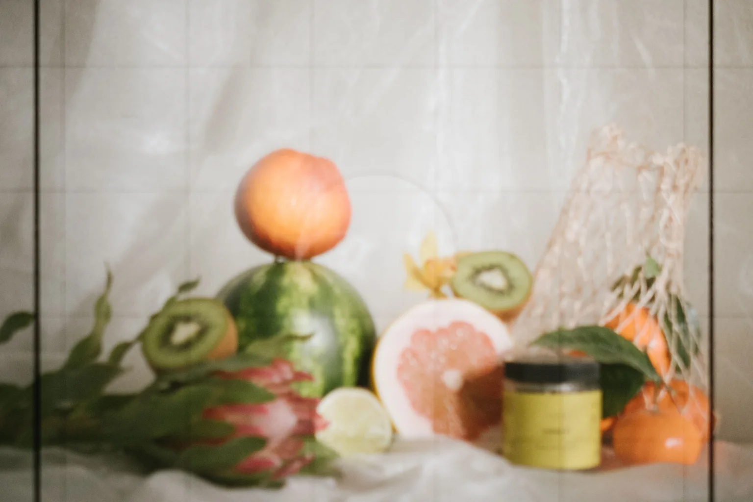 Fresh fruit and a small jar arranged on a white cloth.